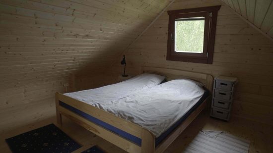 pokój z podwójnym łóżkiem, na poddaszu domku letniskowego